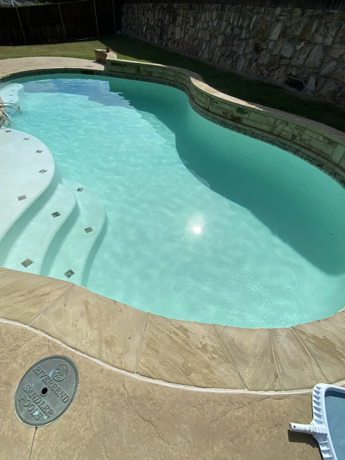 The same pool with clear turquoise water, the steps and tile inlays plainly visible
