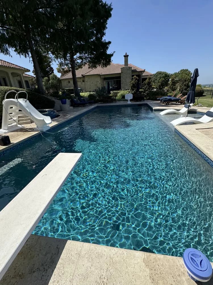 A lakefront pool seen from the far end, with the house beyond it